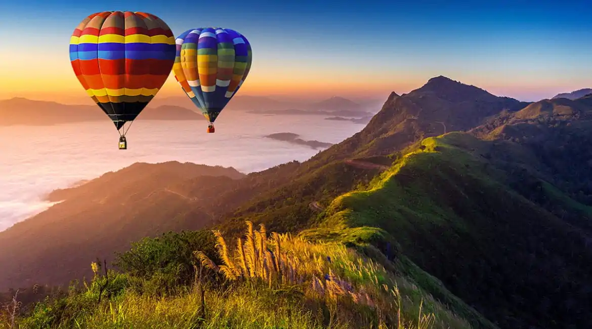 SEO para imagens - Paisagem de neblina matinal e montanhas com balões de ar quente ao nascer do sol.